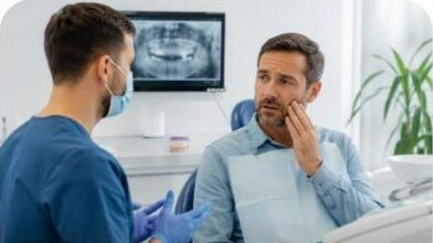 Dentiste en consultation avec un patient touchant sa joue, douleur après pose d'implant dentaire